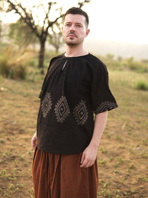 Three quarter view of men's black cotton tunic showing buttoned keyhole neckline and wide short sleeves