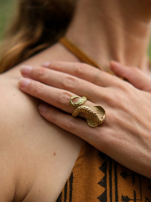 A gold-tone adjustable Sarpa Coil Ring coiled around a finger.