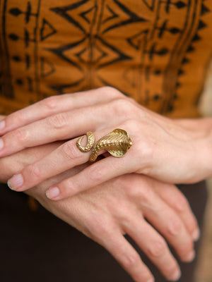 Gold Sarpa Coil Ring coiled around a finger.