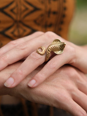 Gold adjustable Sarpa Coil Ring shaped like a cobra resting on a finger.