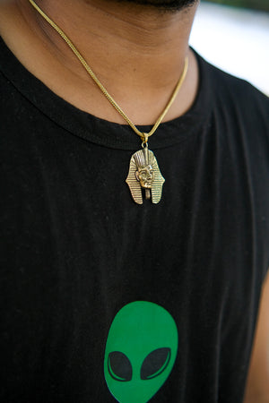 A close-up of a person wearing the Pharaoh Necklace and a black shirt with a green alien face graphic.