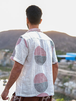 A man with short dark hair stands outdoors, facing away from the camera, wearing a stylish Darlion Shirt. The scenic background features hills and a bright sky.
