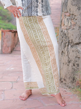 Wearing the Chetra Dhoti, a traditional Indian garment, a person stands barefoot on a stone pathway by an old wall, with only their legs and part of their torso visible.