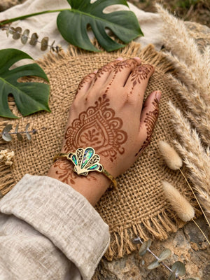 Aabha brass abalone shell cuff bracelet worn on the wrist with henna-decorated hand and linen sleeve