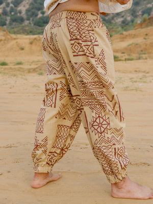 Side view of beige hand block printed harem pants showing wide relaxed leg, brown tribal print and elastic ankle cuff