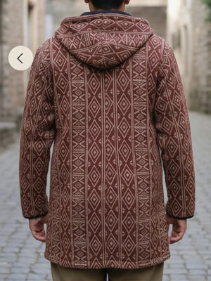 Back view of the maroon and cream Adivasi hooded jacket worn down a cobbled street between stone buildings