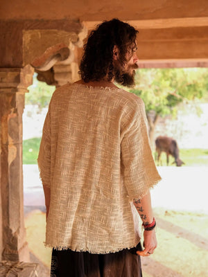 Beige cotton-jute baggy T-shirt back view in a stone corridor, showing the raw frayed back hem