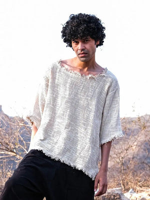 Natural cream cotton-jute T-shirt front view on a model against dry hills, frayed neckline, plain black pants