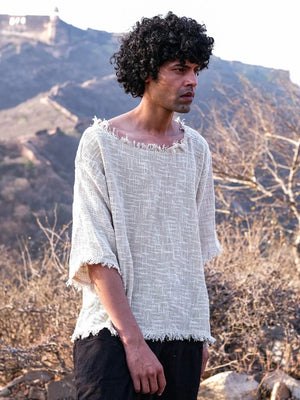 Natural cream frayed cotton-jute T-shirt three-quarter view on a model against dry hills