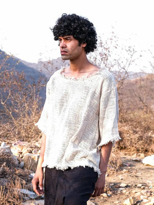 Natural cream cotton-jute T-shirt three-quarter view, model looking down, frayed neckline, dark pants