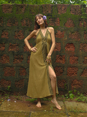 Green Devi Maxi Dress with front slit, model walking by red brick wall, full length