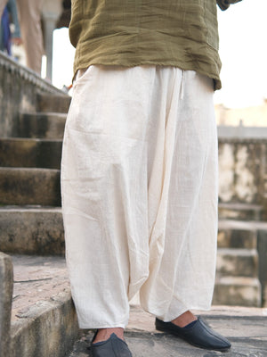 Close view of natural cream harem pants from waist to ankle with an olive tee, gathered legs tapering above black loafers.