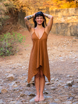 Dumati Dress in earthy brown cotton, front view on a barefoot model showing the deep V halter neckline and handkerchief hem
