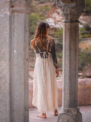 Back view of cream halter maxi dress with criss-cross cord ties, stone arches