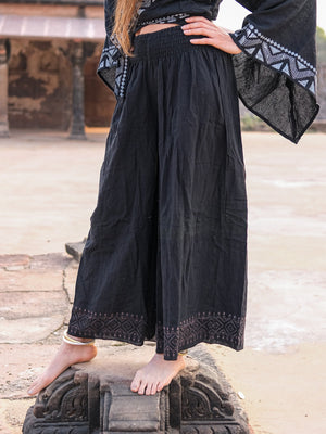 Black Medusa palazzo pants with grey block print hem border and a smocked waist, worn with a black bell sleeve top