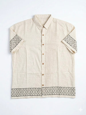 Flat lay of the Meher Shirt, natural cotton body with black handblock geometric wave borders on both sleeves and hem