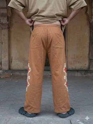 Back view of beige Naqsh cotton trousers with a red geometric print along the side seam and patch pockets