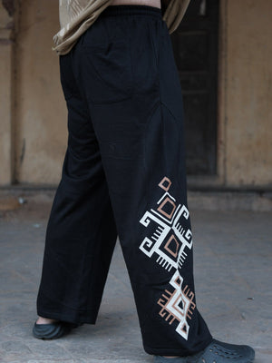 Back view of black Naqsh trousers showing a patch back pocket and the geometric print edging the wide leg