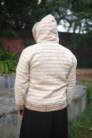 Close back view of the Nomad cotton jacket with the hood up, geometric print band along the hem