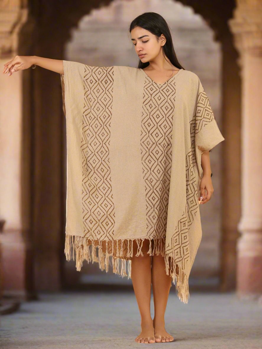 Beige Tula kaftan in hand block print cotton with tassel hem, worn over one shoulder at a stone archway