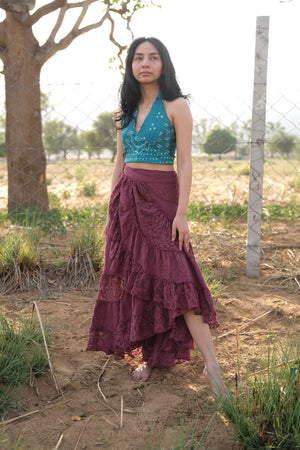 Wine red layered wrap skirt with one leg stepping forward in a dusty field, diagonal openwork lace panel across the front