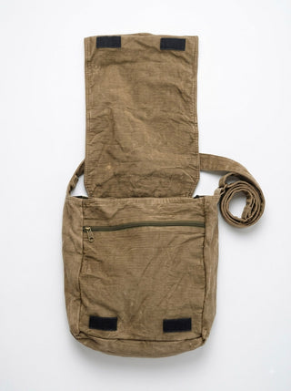 The Vanika Sling Bag is a brown canvas bohemian crossbody featuring artisanal craftsmanship, a long strap, a front zipper pocket, and a flap cover that opens to reveal the interior. The bag appears flat and slightly wrinkled against a plain background.