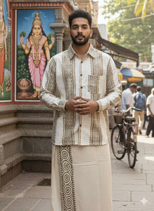A man in traditional Indian attire stands with hands clasped, wearing the Dwara Shirt—a cream and brown shirt paired with a veshti. He is outdoors near a temple, with a colorful deity painting and a bicycle in the background.