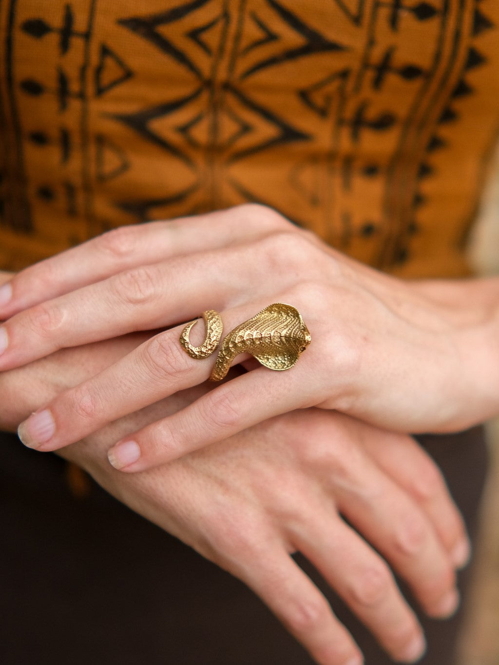 Gold Sarpa Coil Ring coiled around a finger.