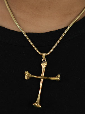 The Eternal Relic Necklace features a gold pendant shaped like two bone-like pieces, creating an eye-catching gothic look when worn over a black shirt.