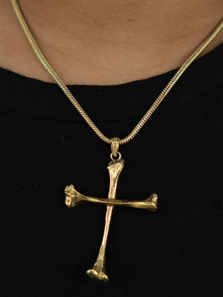 The Eternal Relic Necklace features a gold pendant shaped like two bone-like pieces, creating an eye-catching gothic look when worn over a black shirt.