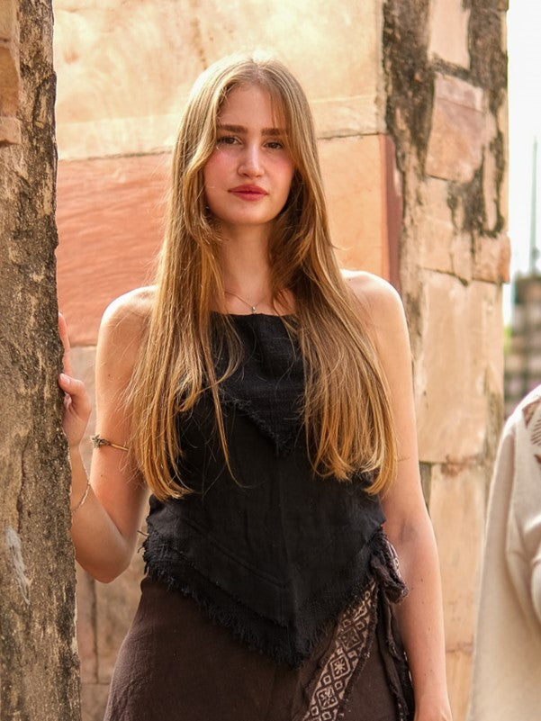 A young woman with long, straight blonde hair wears the Chiara Crop Top in black and stands by a stone wall, looking at the camera with a neutral expression.