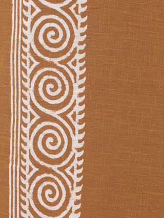 The Tribal Dhoti fabric showcases a brown background with a white vertical pattern in traditional Indian style. Its design features spirals intertwined with leafy motifs and bordered parallel lines, reminiscent of Rajasthani hand block-print, all on a textured woven surface.