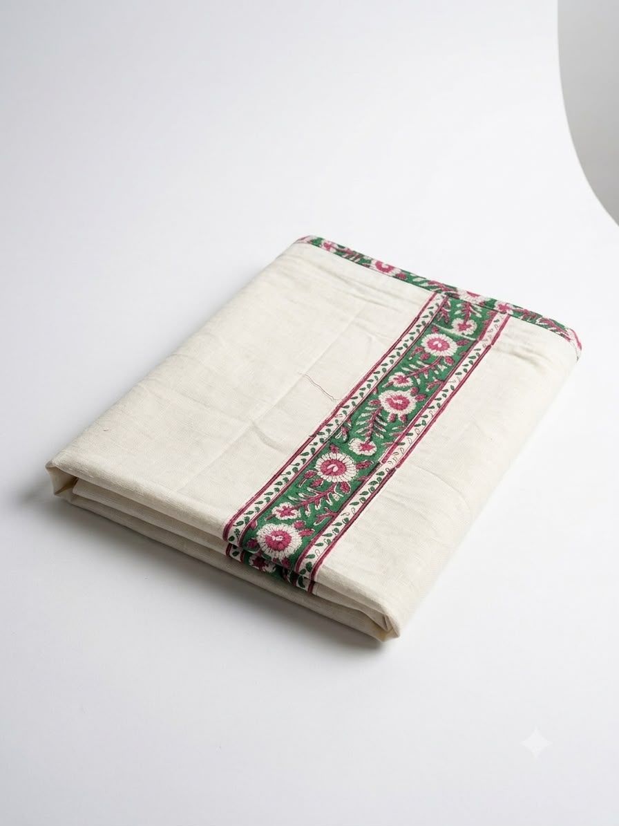 A folded Veena Dhoti in white, featuring a decorative green and pink floral border reminiscent of a traditional South Indian mundu, displayed on a plain white surface.