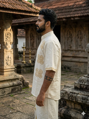 A bearded man stands sideways in an ancient stone temple, surrounded by carved pillars and lamps, wearing the Midnight Nomad kurta with handblock prints.