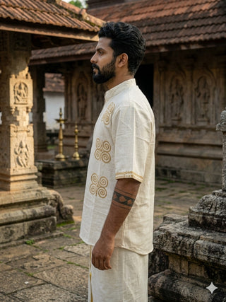 A bearded man stands sideways in an ancient stone temple, surrounded by carved pillars and lamps, wearing the Midnight Nomad kurta with handblock prints.