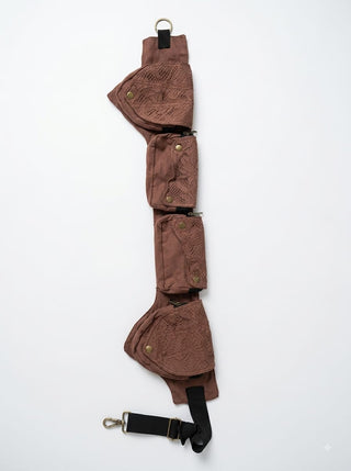 Add bohemian flair to your Rustic Festival Bag ensemble with this brown utility belt, designed with three pouches featuring lace patterns, brass buttons, and metal rings on each end. Laid flat against a white background, it’s the perfect accessory for elevating your look.