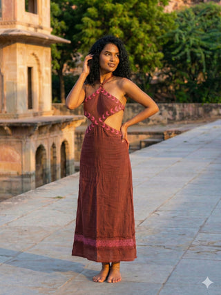 Aadhya Maxi Dress in maroon block print, front view with hand raised to her hair in a palace courtyard