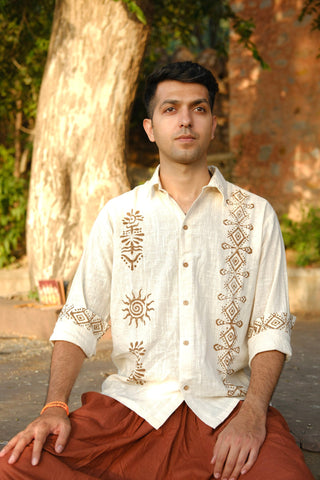 Seated model in the off-white hand block printed shirt, sun and spiral motifs across the placket