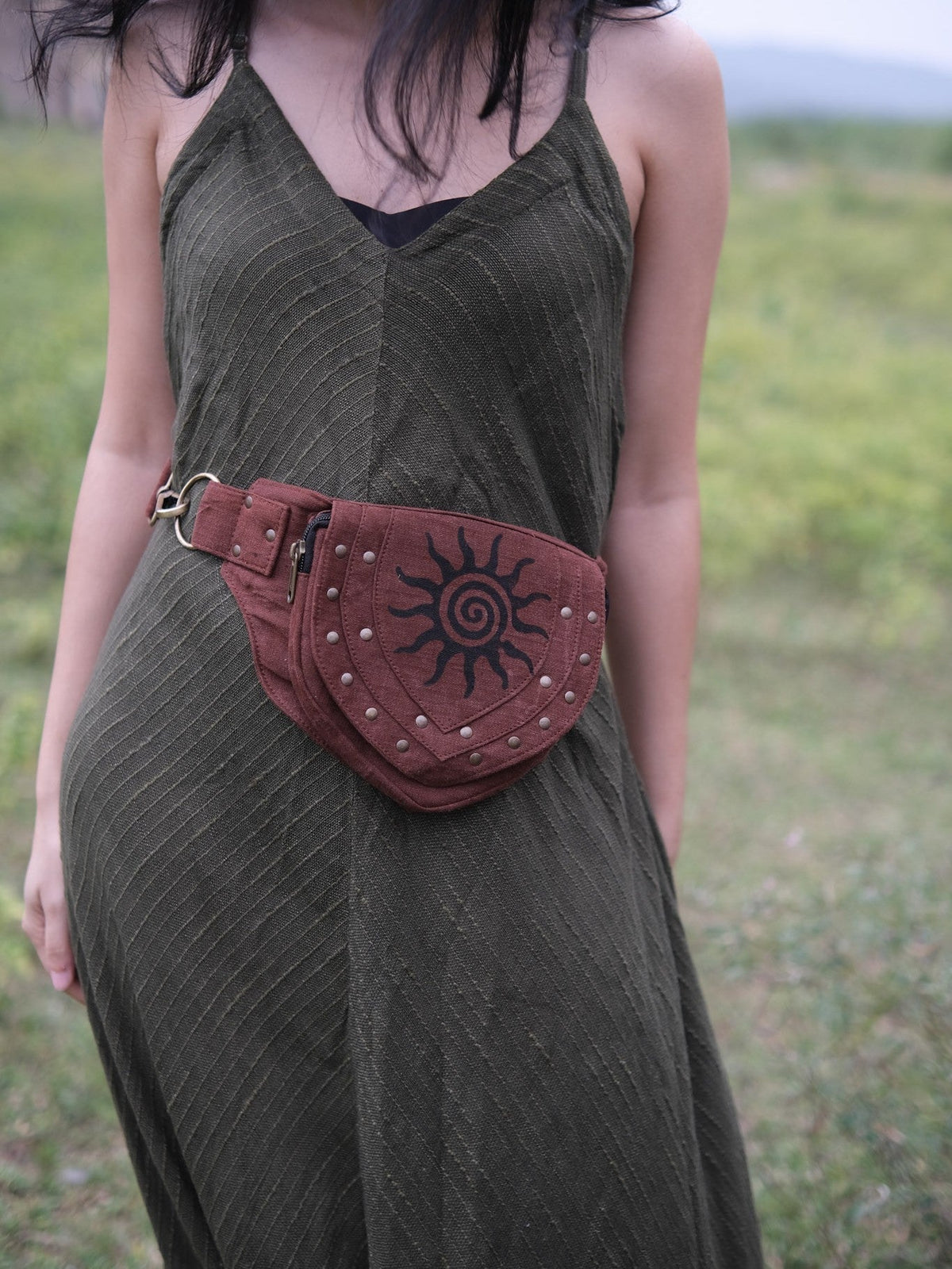 Maroon Aditya Festival Bag slung crossbody over an olive maxi dress in a grassy meadow