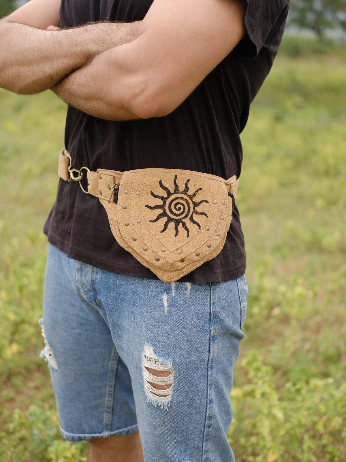 Close view of the tan Aditya Festival Bag sun spiral print worn with ripped denim shorts outdoors