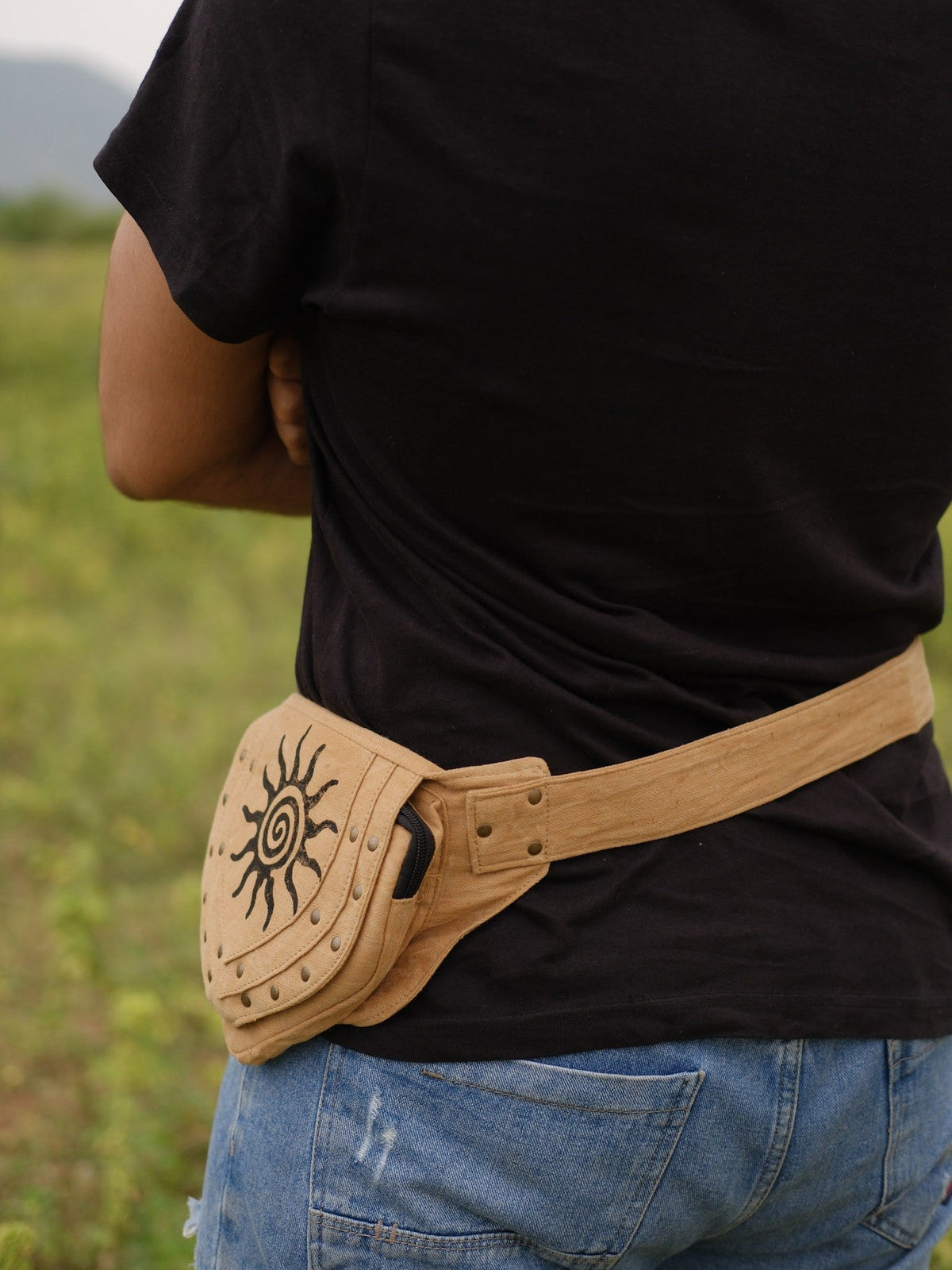 Back view of the tan Aditya Festival Bag showing the adjustable waist strap and rear studded panel