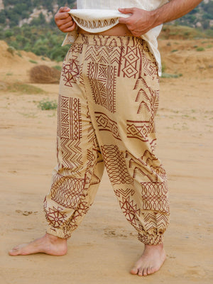 Front view of beige cotton harem pants with brown tribal star and diamond motifs, drawstring waist and side pockets