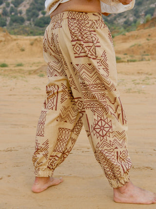 Side view of beige hand block printed harem pants showing wide relaxed leg, brown tribal print and elastic ankle cuff