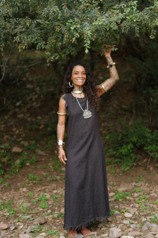Afra Maxi Dress black cotton with one arm raised under green forest canopy