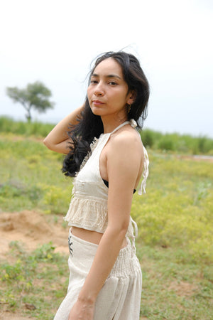 Cream Amra fringe halter crop top styled with a wide leg pant and shell belt