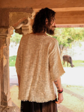 Beige cotton-jute baggy T-shirt back view in a stone corridor, showing the raw frayed back hem