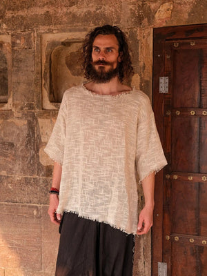 Beige cotton-jute oversized T-shirt front view in a carved stone doorway, frayed neckline and hem