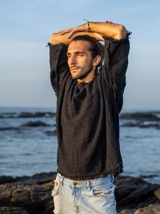 Black baggy jute T-shirt with arms raised overhead, showing the frayed sleeve hems and relaxed body