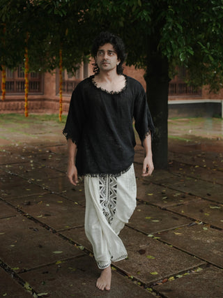 Black baggy knit cotton-jute T-shirt full length on a model walking barefoot, frayed edges, white dhoti pants