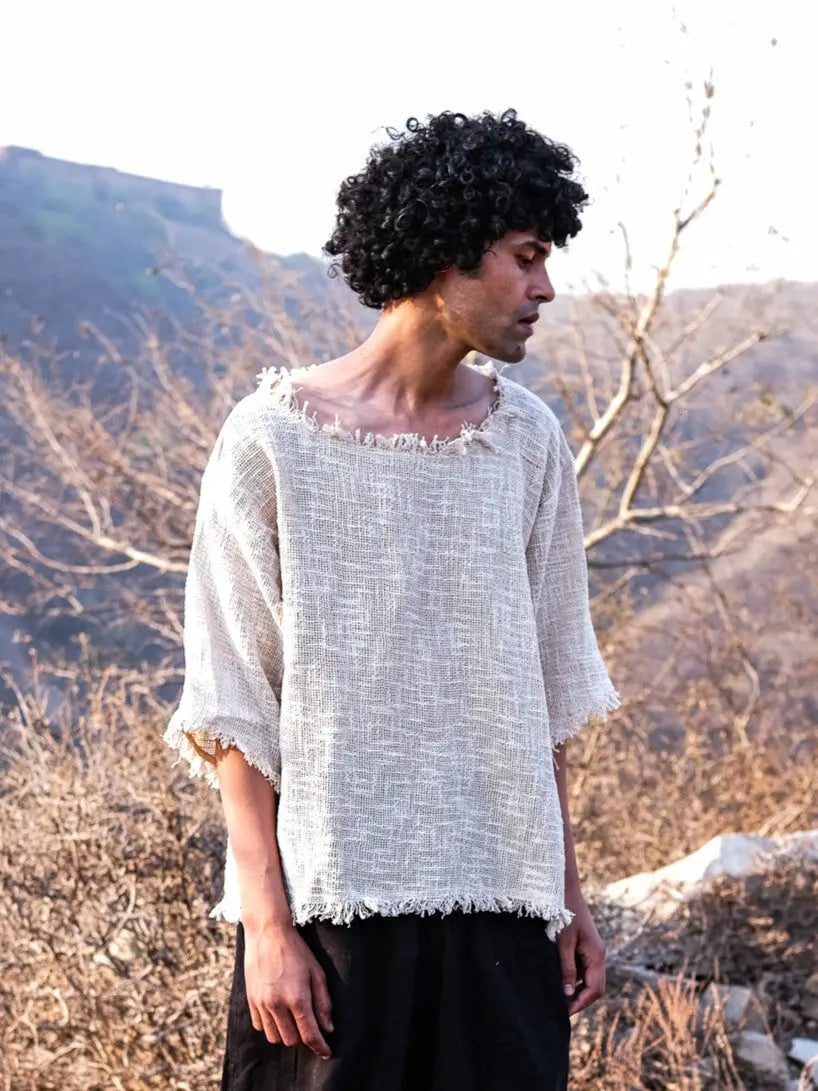 Natural cream cotton-jute baggy T-shirt on a model outdoors, open weave, frayed neckline, worn with dark trousers